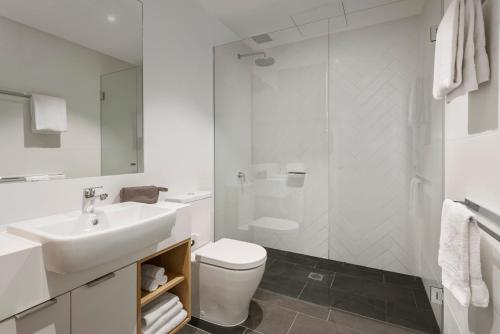 a white bathroom with a sink and a toilet at Quest Goulburn North in Goulburn