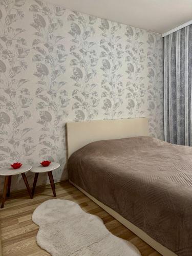 une chambre avec un lit et un mur recouvert de papier peint dans l'établissement Sweet Home, à Kosovo Polje