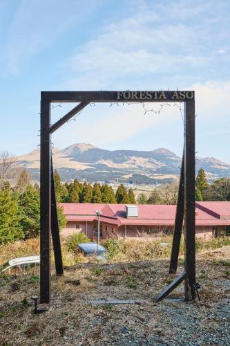a metal arch with a sign on it in a field at フォレスタ阿蘇車帰 in Aso