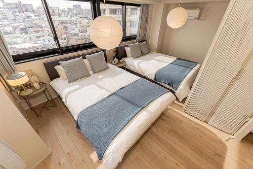 two beds in a room with a large window at Mi-Hotel Kameido in Tokyo