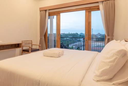 a bedroom with a white bed with a balcony at Nang Aji House in Ungasan