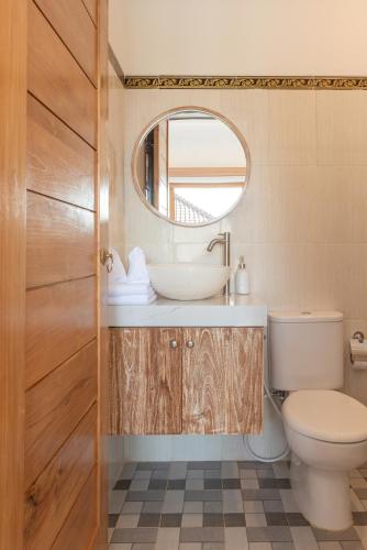 a bathroom with a sink and a toilet and a mirror at Nang Aji House in Ungasan