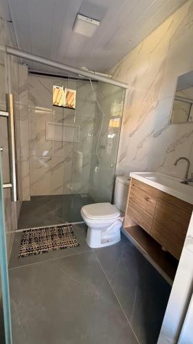 a bathroom with a shower and a toilet and a sink at Sitio em Capim Branco in Capim Branco