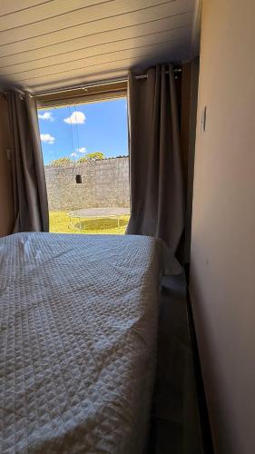 a bed in a small room with a window at Sitio em Capim Branco in Capim Branco