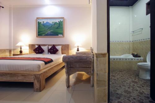 a bedroom with a bed and a bathroom with a toilet at Alam Terrace Cottages in Ubud