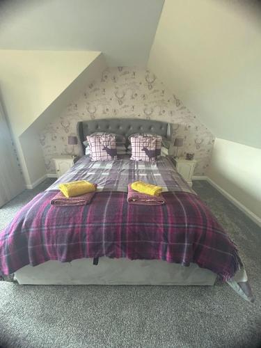 a bedroom with a bed with a plaid blanket and pillows at Acorn Apartment in Dufftown