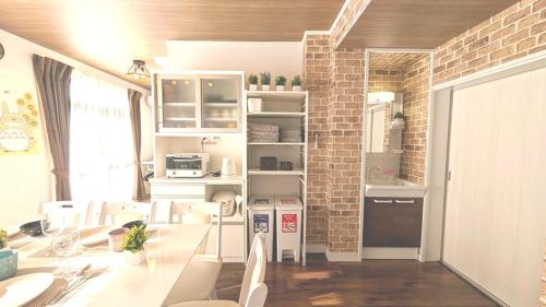 a kitchen with white tables and chairs and a brick wall at LandHouse Seto Hagiyamadai ジブリへ車で約10分 MAX9人 駐車場2台 in Seto