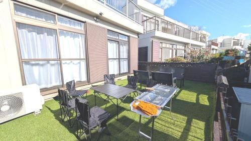 a patio with a table and chairs on the grass at LandHouse Seto Hagiyamadai ジブリへ車で約10分 MAX9人 駐車場2台 in Seto