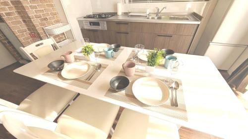 a kitchen table with two white plates and plants on it at LandHouse Seto Hagiyamadai ジブリへ車で約10分 MAX9人 駐車場2台 in Seto