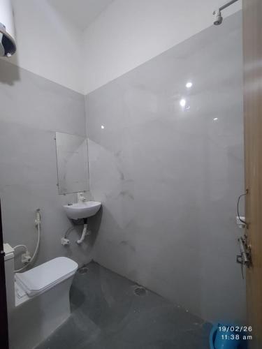 a white bathroom with a toilet and a sink at Naval Kishori Kunj in Vrindāvan