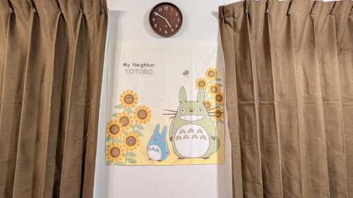 a clock on a wall next to a curtain at LandHouse Seto Hagiyamadai ジブリへ車で約10分 MAX9人 駐車場2台 in Seto