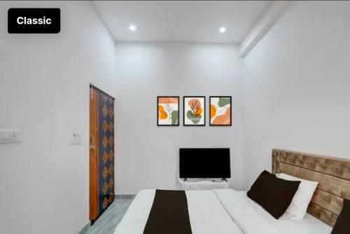 a white bedroom with a bed and a tv at Arctic Inn in Gorakhpur