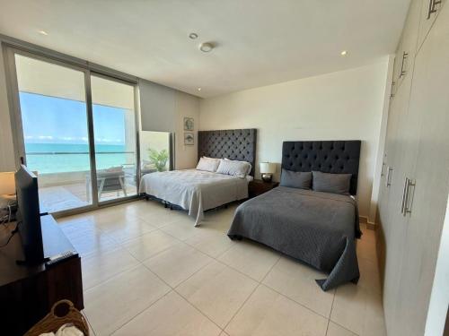 a bedroom with a bed and a television and the ocean at Departamento con acceso directo a la playa en Velamar in Altamira