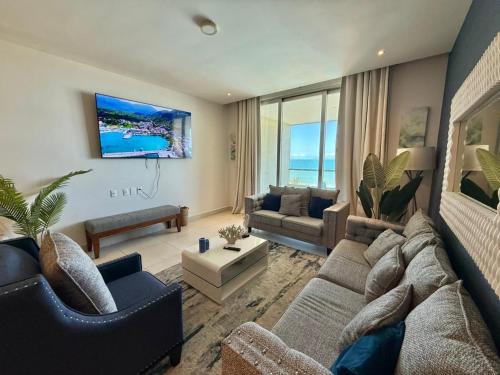 a living room with a couch and a tv at Departamento con acceso directo a la playa en Velamar in Altamira