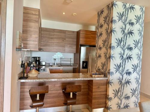 a kitchen with wooden cabinets and a counter with stools at Departamento con acceso directo a la playa en Velamar in Altamira