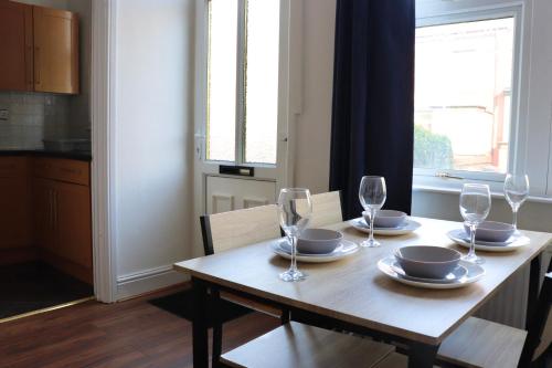 a wooden table with wine glasses and plates on it at Perfect Getaway 2 bedroom house with parking in Beeston Hill