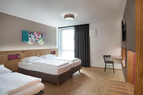 ein Hotelzimmer mit 2 Betten und einem Stuhl in der Unterkunft fab Hotel in München