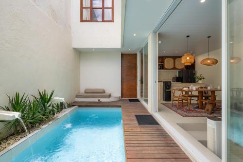 a swimming pool in the middle of a living room and a house at SandWave Villa by Betterplace in Ungasan
