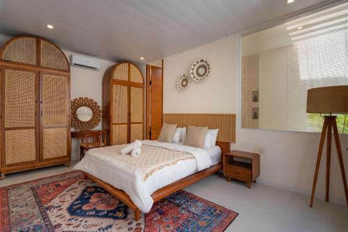 a bedroom with a large bed and a rug at SandWave Villa by Betterplace in Ungasan