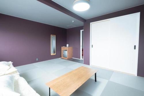 a room with a bed and a wooden table at B Cycleトリプルルーム in Biei