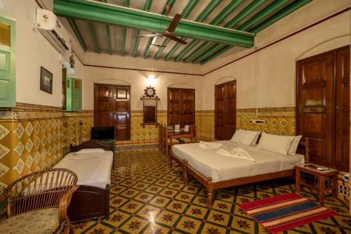 a bedroom with two beds in a room at Chettinadu Mansion – An Authentic Heritage Palace in Kānādukāttān