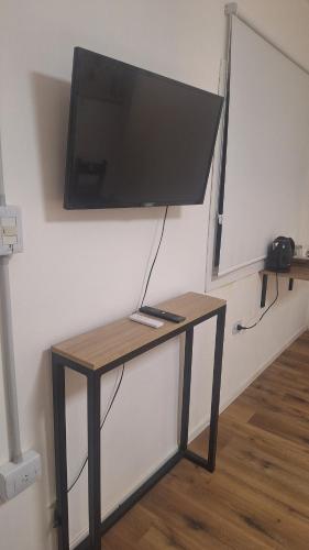 a tv hanging on a wall with a table at Hospedaje Sierras Chica in Quines