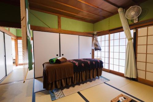 a bedroom with a bed in a room with windows at 杜の酵素808 in Takaharu