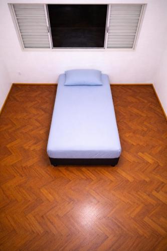 a white bed sitting on a wooden floor in a room at Quarto em Barretos, simples com paz e harmonia in Barretos