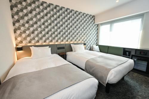 a hotel room with two beds and a window at GRIDS PREMIUM HOTEL OSAKA NAMBA in Osaka