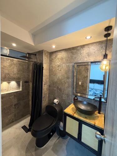 a bathroom with a black toilet and a sink at Comodidad, sol y descanso total in Melgar