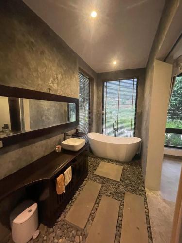 a bathroom with a tub and a large window at emoi valley bavi in Ba Vì