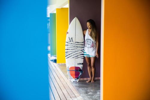 a woman is standing next to a surfboard at Blue Coco in Keramas