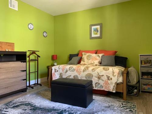 a bedroom with green walls and a bed and a ottoman at Poppy's Place in Chanute