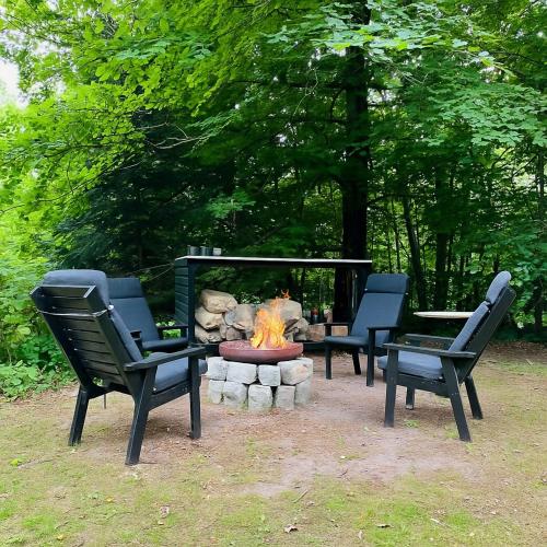 three chairs sitting around a fire pit with a fire pit at Architectural Cottage On 7000 Sqm Nature Plot in Hadsund