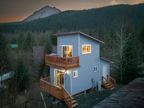 a house with a deck and a mountain in the background at Glacier Creek Cabins in Seward