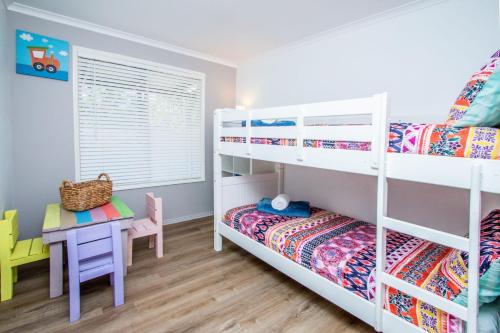 a bedroom with two bunk beds and a table at Canny Breeze in Agnes Water