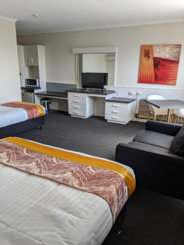 a hotel room with two beds and a desk at Parklane Motel in Launceston