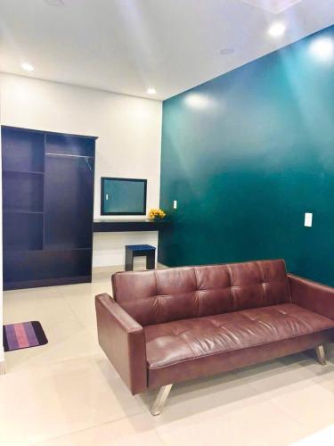 a brown leather couch in a living room with a tv at Hưng Phú Hotel HCM in Ho Chi Minh City