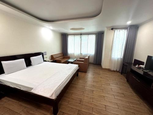 a bedroom with a bed and a couch and a television at Mong Yen Hotel in Cao Lãnh