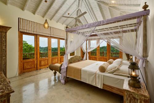 a bedroom with a canopy bed and a balcony at The Divine Villa in Talpe