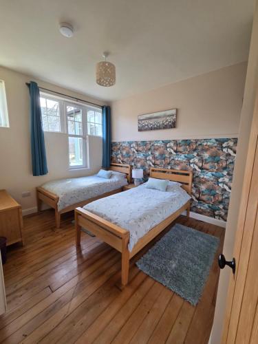 a bedroom with two beds and a window at Siskin Cottage in Lochgilphead