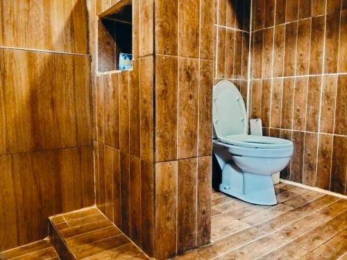 a bathroom with a toilet in a wooden wall at Satu Lingkung in Tetebatu