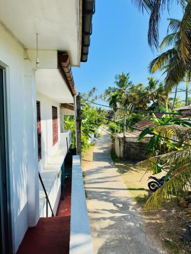 a balcony of a building with a sidewalk and palm trees at TM Villa Madiha in Matara