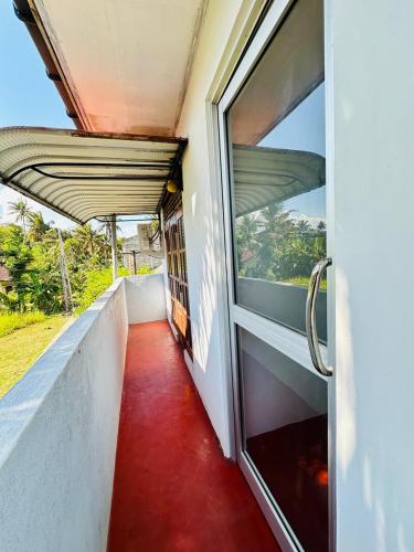 an open door to a balcony with a red floor at TM Villa Madiha in Matara