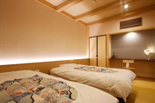 two beds in a room with a cross on the wall at Ryokan Beniayu in Nagahama