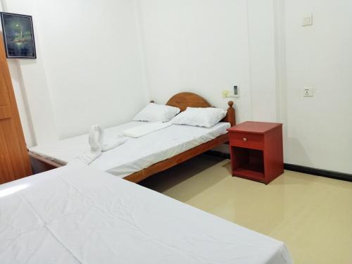 two beds in a room with a nightstand and a bed at Southern Surf Villa in Dickwella