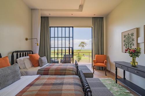 a bedroom with a bed and a desk and a window at Rubi Ranch Lakehouses in Naivasha