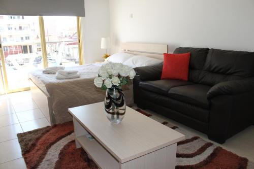 a living room with a couch and a vase of flowers on a table at Tiffany City Apartments in Larnaka
