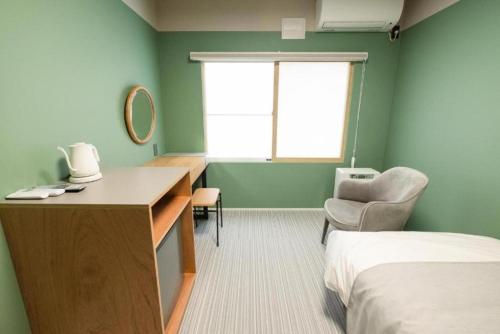 a room with a desk and a bed and a window at B cycle シングルルーム in Biei