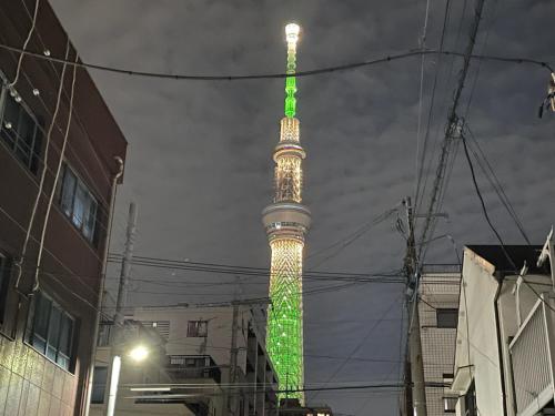 a tv tower lit up in green and yellow at Skytree 12pax Family-Friendly with Indoor Playground in Tokyo